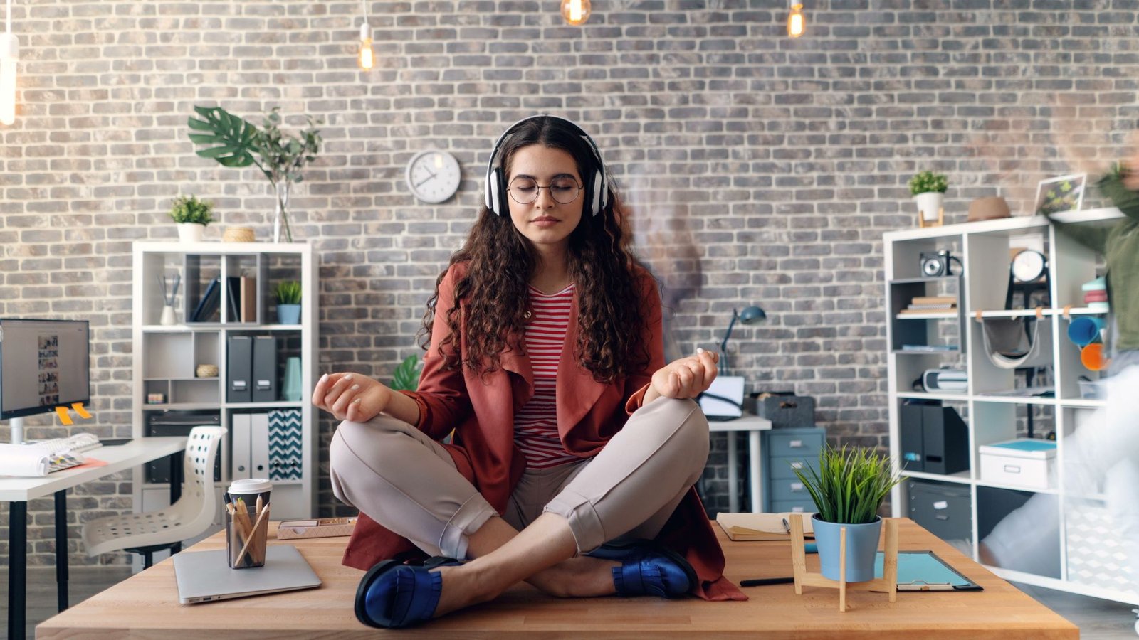 Mulher meditando no escritório com fones de ouvido — yoga e neurociência para estresse crônico