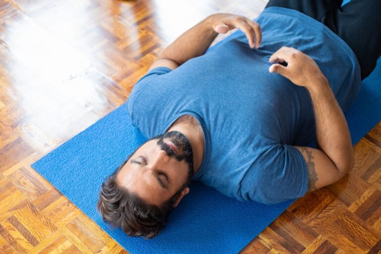 Pessoa praticando posturas suaves de yoga na cama à noite para reduzir a ansiedade antes de dormir
