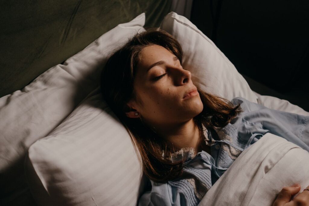 Mulher dormindo profundamente na cama em ambiente escuro ilustrando sono restaurador de qualidade após prática de Yin Yoga e higiene do sono