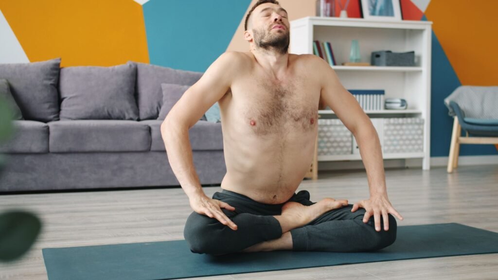 Homem praticando pranayama em torção sentada, com tronco girado e cabeça inclinada para trás, respirando profundamente sobre tapete de ioga