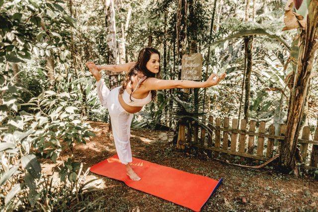 Mulher praticando postura de equilíbrio de yoga (dançarina) ao ar livre em ambiente natural